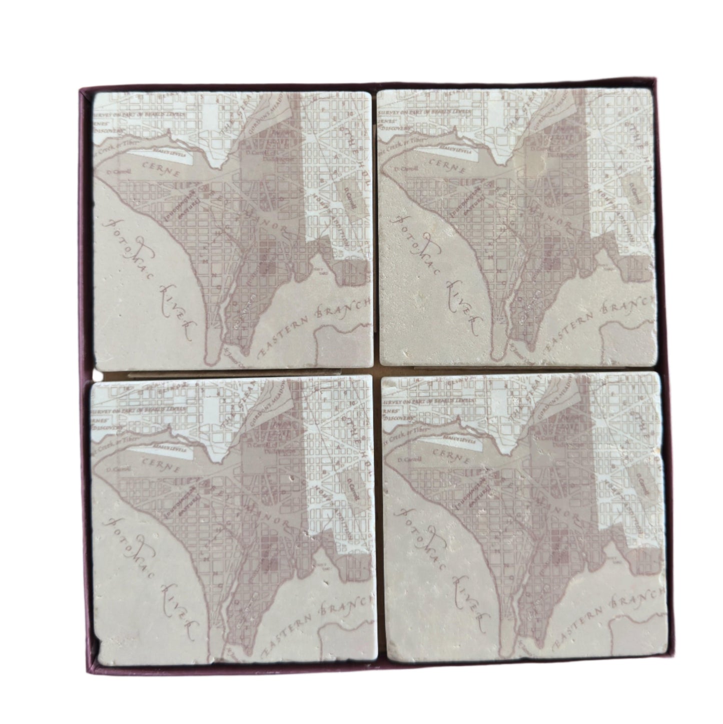 Set of four square tiles with engraved map design on a wooden surface